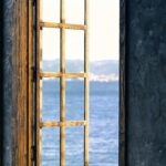 Tranquil scene of an open window with a stunning view of a peaceful lake and distant mountains.